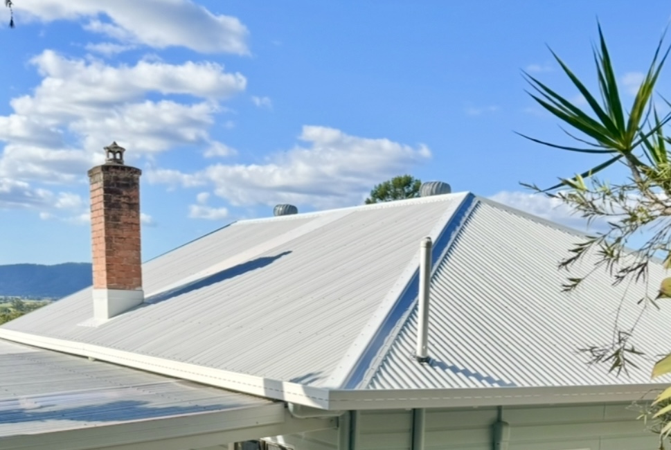 A new white Colorbond hip roof with the original brick chimney kept, with the Tweed ranges behind